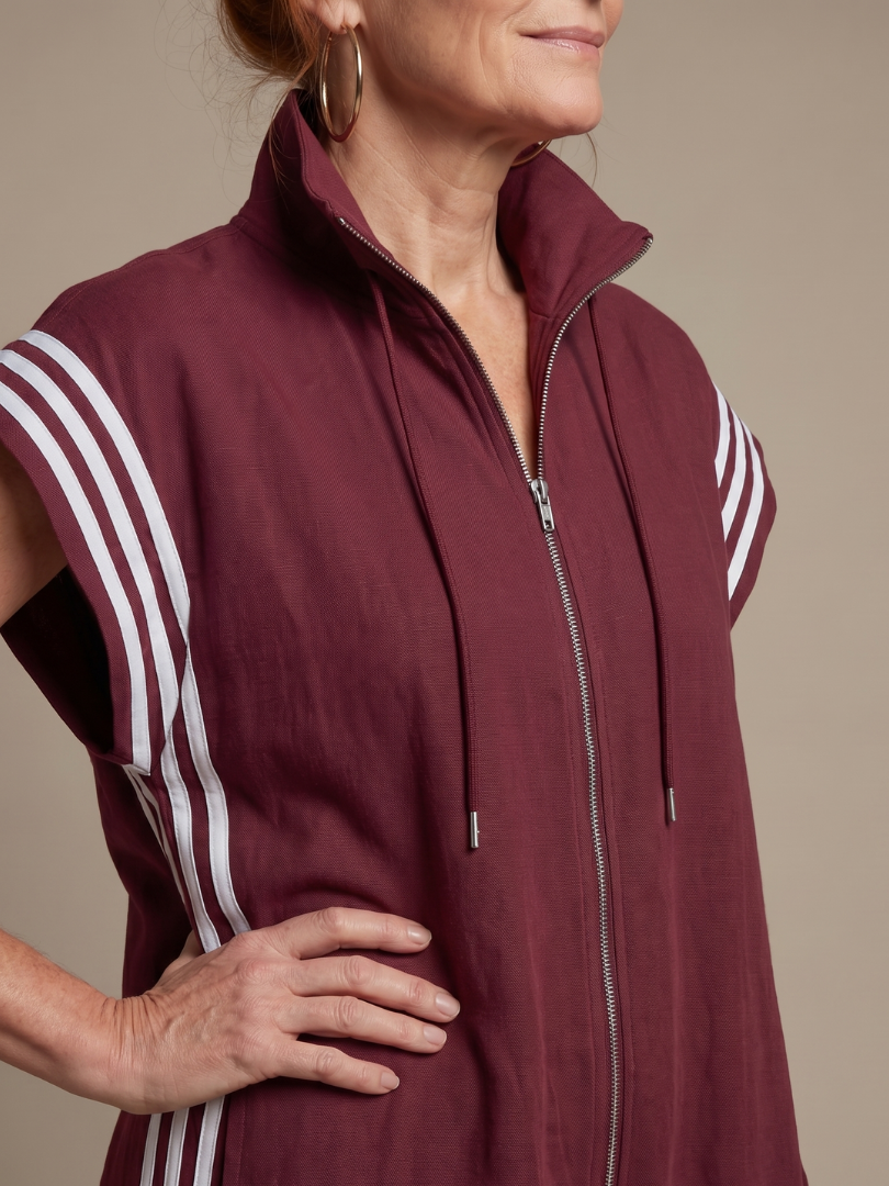 Burgundy zip-front jumpsuit close-up with drawstring hood and white triple stripe trim