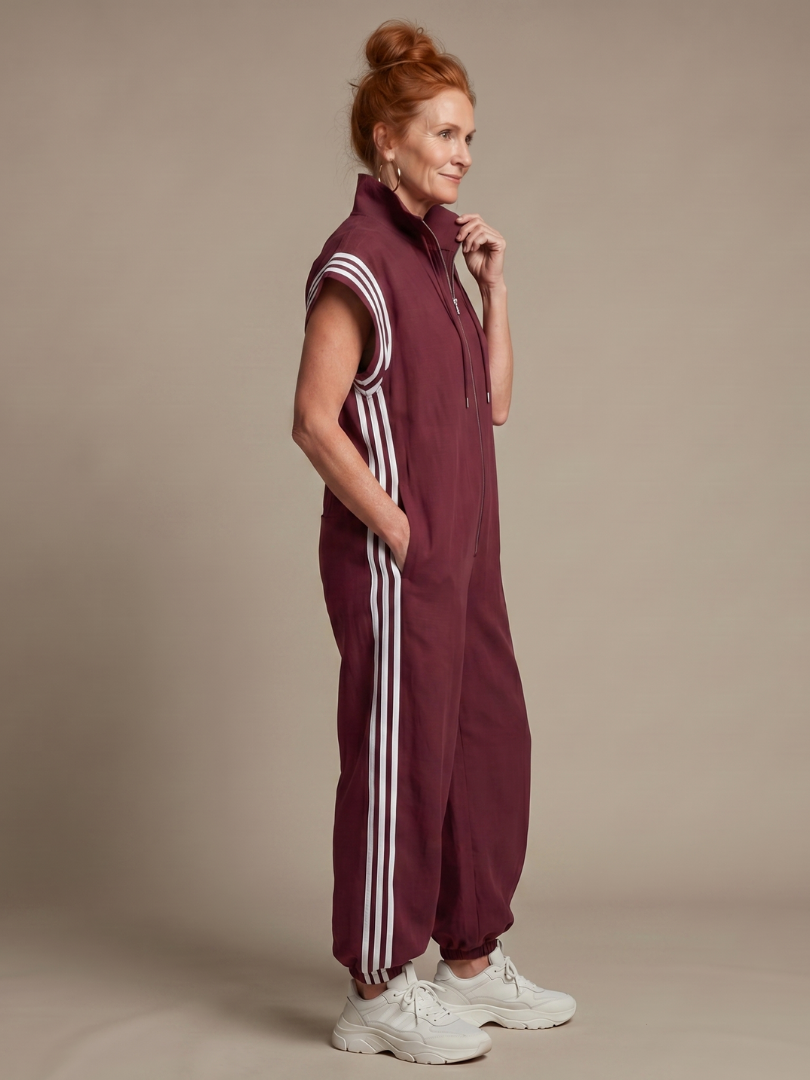 Burgundy zip-front sleeveless jumpsuit with white triple stripe sleeve panels and cuffed legs
