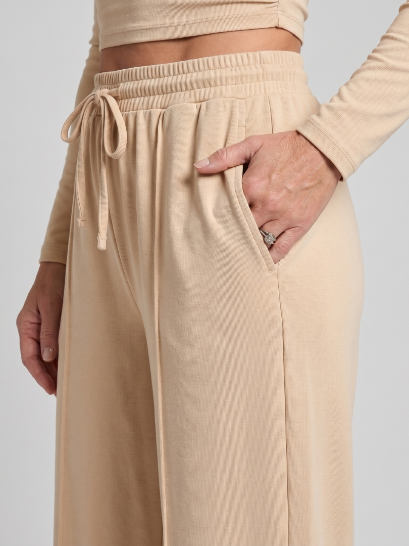 Beige wide-leg pants with elastic waist and drawstring ties (close-up).